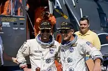 Astronauts Pete Conrad and Richard Gordon pose in front of the recovery helicopter aboard USS Guam on 30 December 1966.