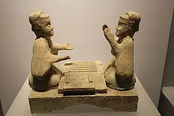 Image 27Han dynasty glazed pottery tomb figurines playing liubo, with six sticks laid out to the side of the game board (from Board game)