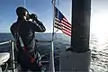 A Sonar Technician stands lookout in the sail aboard Minnesota as the boat transits Port Canaveral, FL.